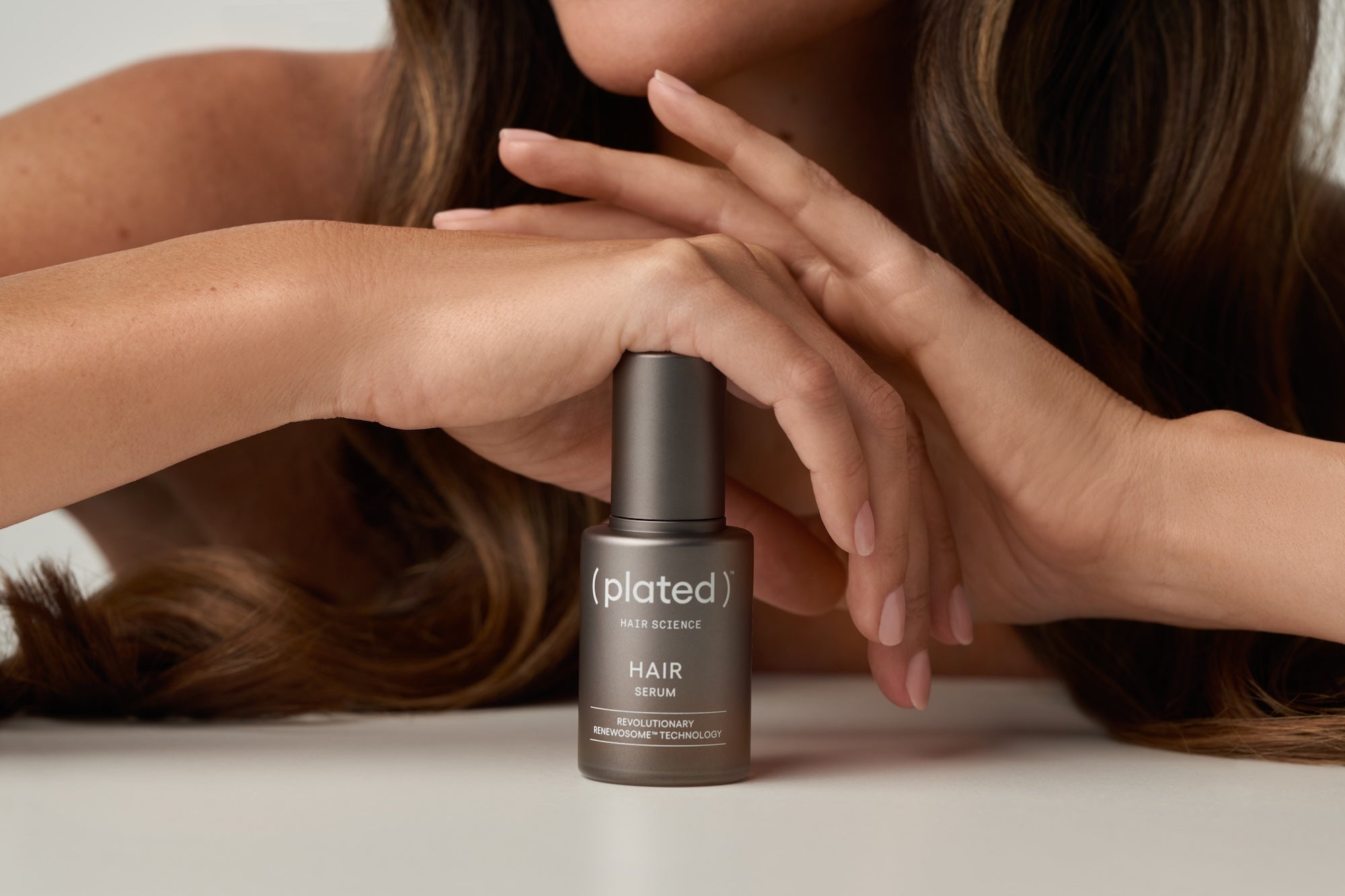 Woman holding plated HAIR Serum 