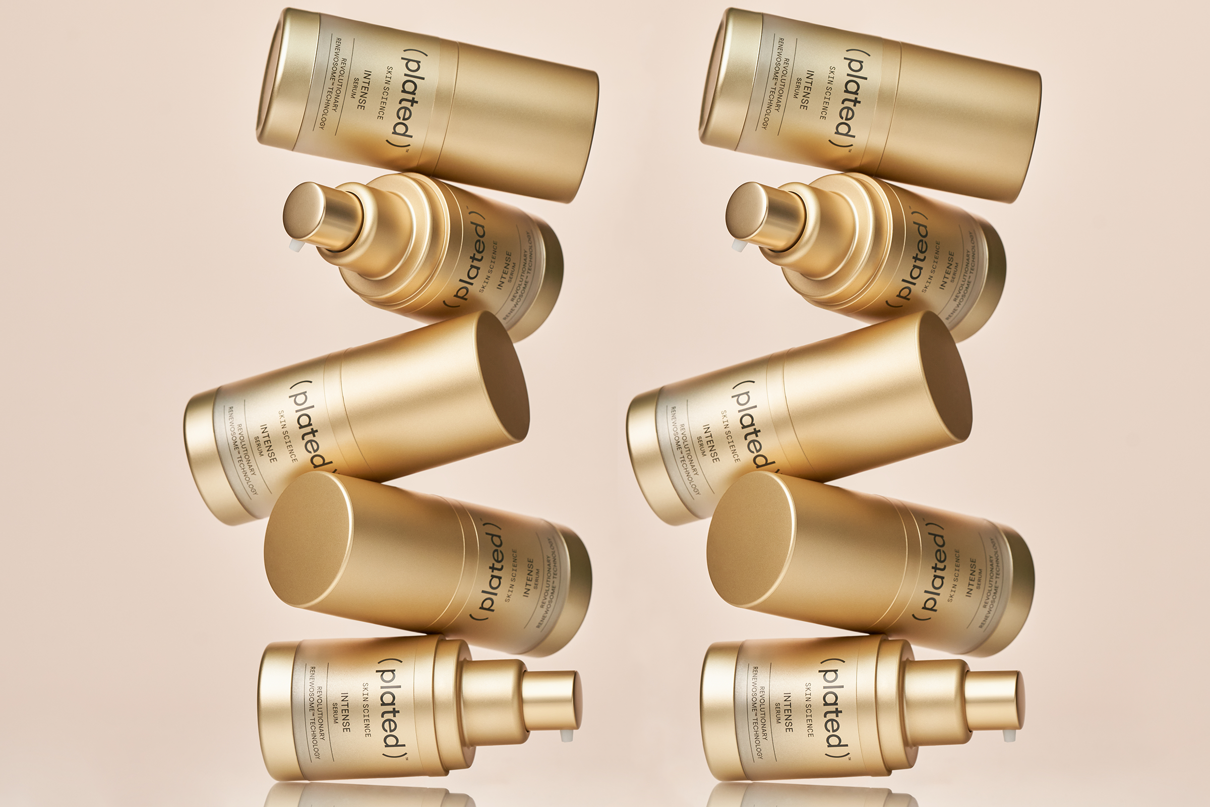 Stack of gold bottles labeled ( plated ) Skin Science INTENSE Serum on a beige background