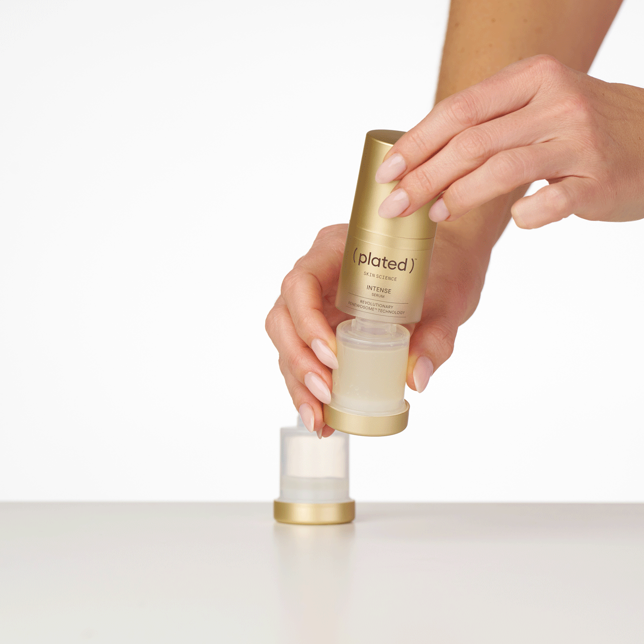 Hands holding a ( plated ) Skin Science INTENSE Serum bottle and replacing the refill cartridge on a white background - Step 6 of the Refill Sequence