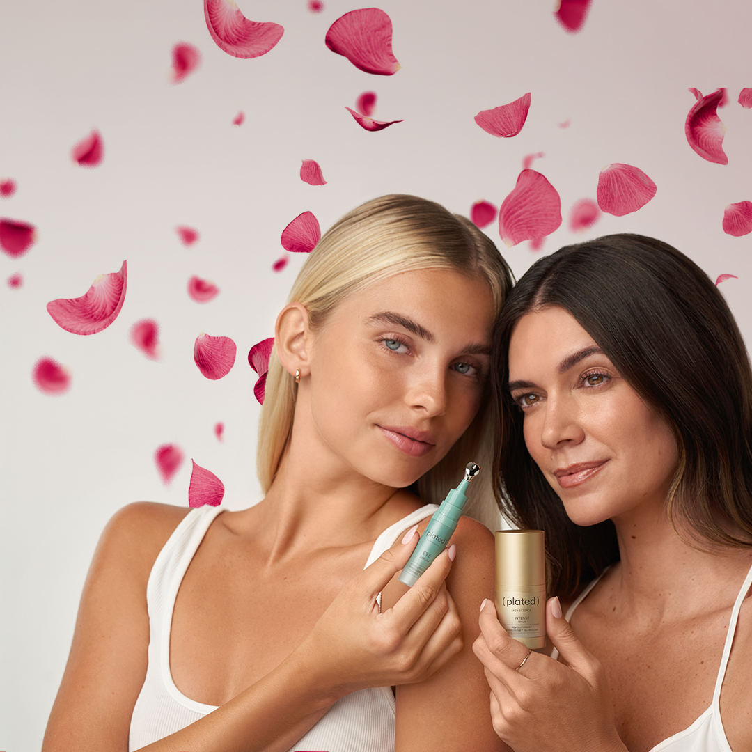 Models holding INTENSE & EYE Serum skincare products with pink flower petals on a grey background